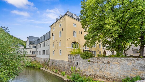 A historic building with a stone wall and a river.