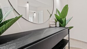 A modern bathroom with a black vanity, a large mirror, and a potted plant.