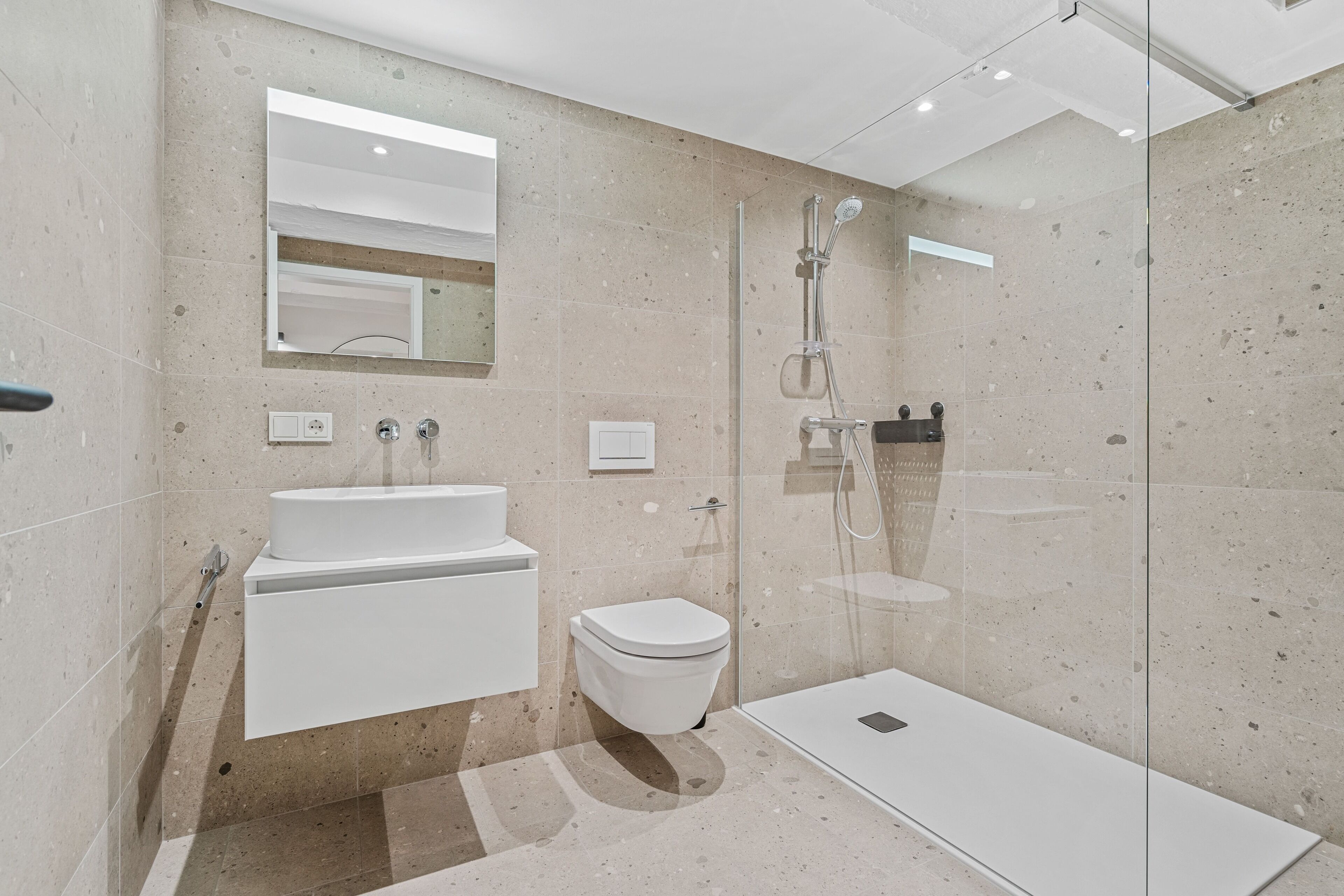 Une salle de bain moderne avec une douche à parois de verre, un lavabo blanc et des toilettes.