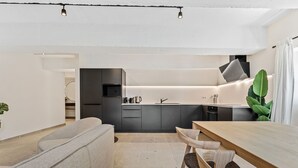 A modern kitchen with dark cabinets, a wooden dining table, and a large plant.
