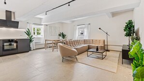 A spacious living area with a large sectional sofa, a dining table, and a kitchen area with modern appliances.