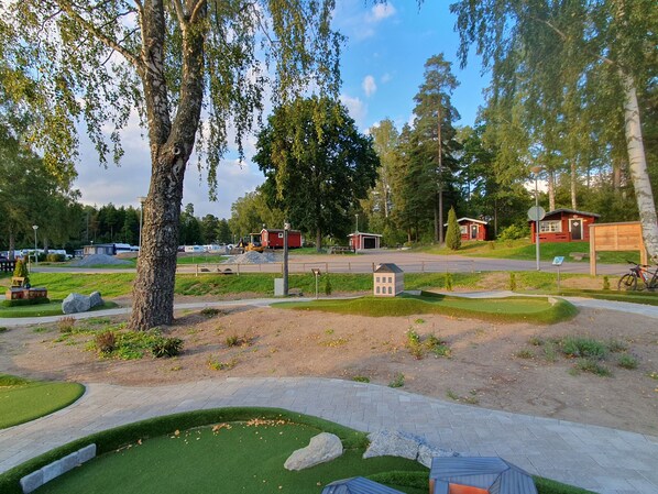 A park with a model building, a playground, and a red cabin.