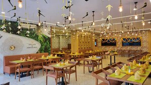 A restaurant with wooden furniture, hanging light fixtures, and a decorative wall. - Hotel Plaza Airport Zone (Hyderabad)