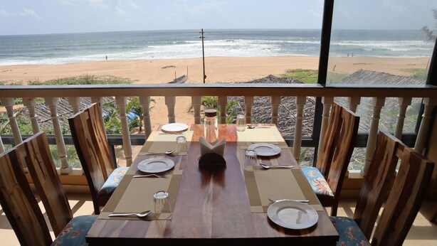 A dining table set for four with a view of the beach.