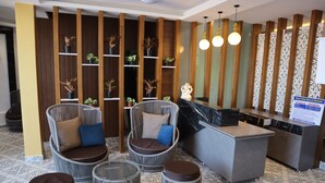A reception area with wicker chairs, a reception desk, and a decorative plant wall.