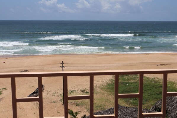 A beach with waves, a sandy shore, and a utility pole. - Sun In Sea Beach Resort (Calangute)