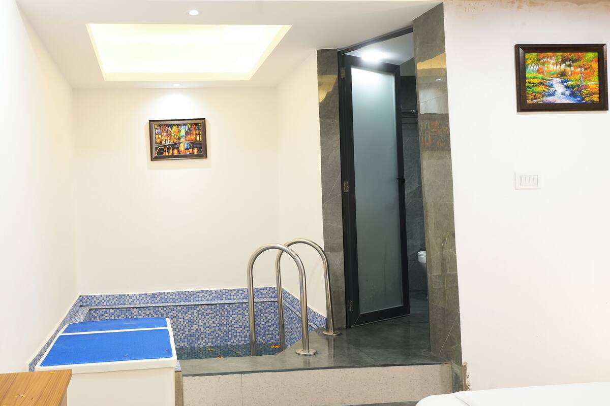 A room with a flat-screen TV, a small painting, a blue-tiled shower area, and a glass shower door.