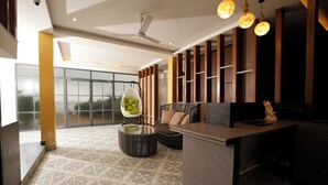 A modern interior with a glass door leading to an outdoor area, a hanging chair, a round coffee table, and a reception desk.