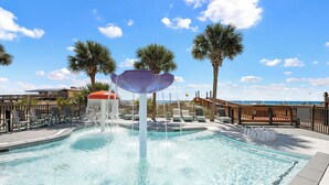 A swimming pool with a water feature, palm trees, and a view of the beach. - NEW RENTAL - Updated Beach Front - Seawind 703 - Signature Properties (Gulf Shores)