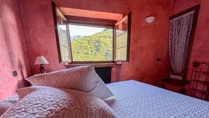 Ein Schlafzimmer mit einem großen Bett, einem Fenster mit Blick auf einen Wald und einer Heizung.