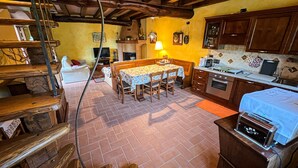 Eine rustikale Küche mit Holzbalken, einem Esstisch und einem eingebauten Backofen.