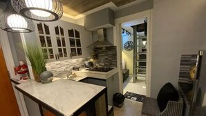 Een moderne keuken met een marmeren aanrecht, roestvrijstalen apparatuur en hanglampen.