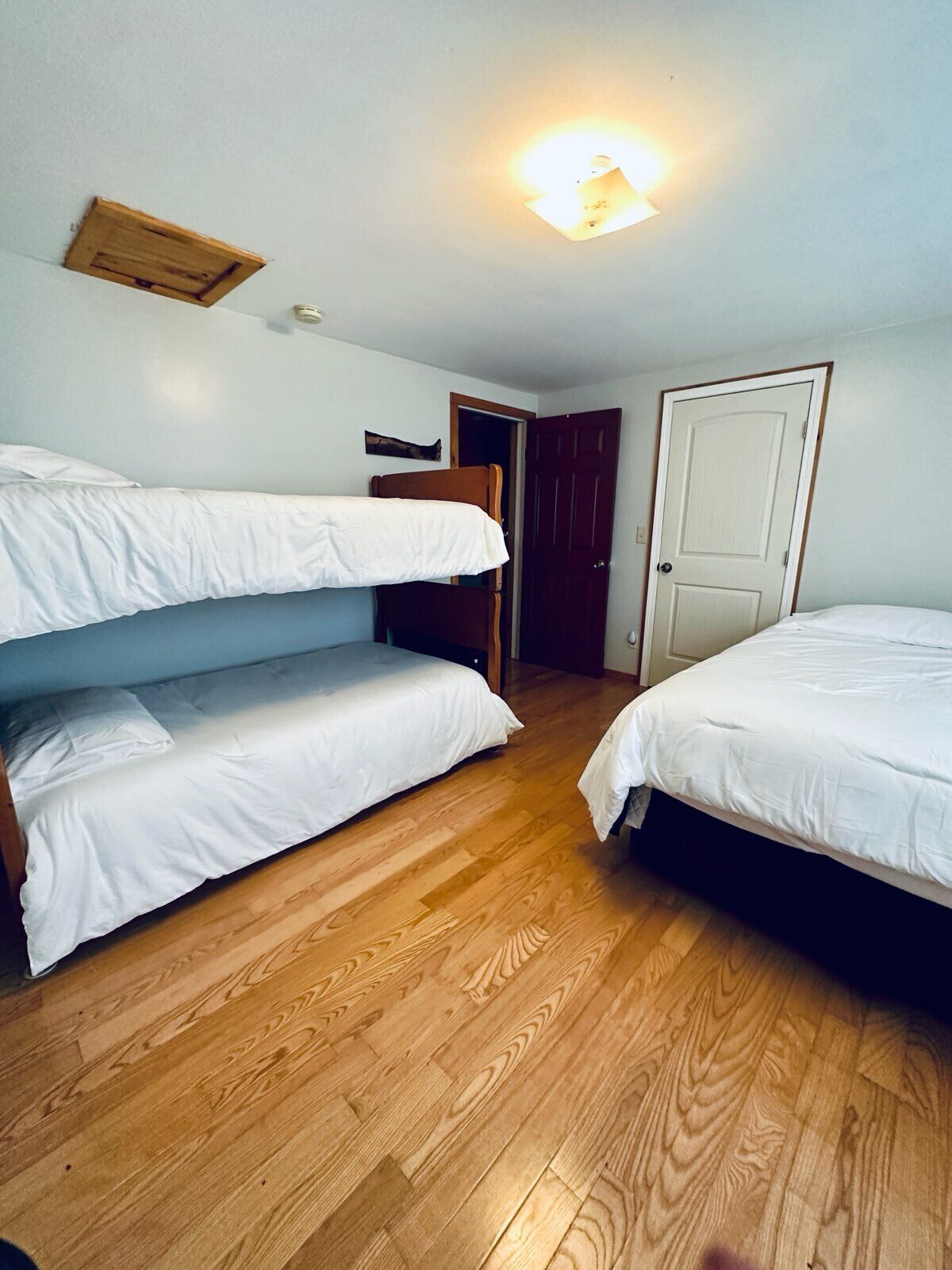 Una habitación con dos literas, piso de madera, una puerta y una lámpara.