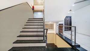 Una escalera con barandilla, un extintor y una puerta con un número.
