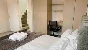 A hotel room with a bed, a desk, a chair, and a staircase. - Your Ideal Guesthouse Getaway (Oxford)