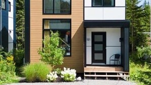 A modern two-story house with a prominent black roof, large windows, and a visible number '121' on the front door. - Cerf Blanc | Sauna & Piscine by Alchalet (Pont-Rouge)