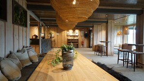 Una habitación amplia con una larga mesa de madera, una lámpara de fibra y un centro de mesa con planta.