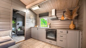 Una cocina con armarios grises, horno empotrado y ventana con vista a follaje.