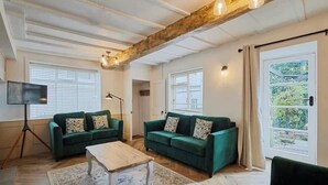 A spacious living room with two green sofas, a wooden coffee table, and a floor lamp. - Host & Stay | Cragg Cottage (Whitby)