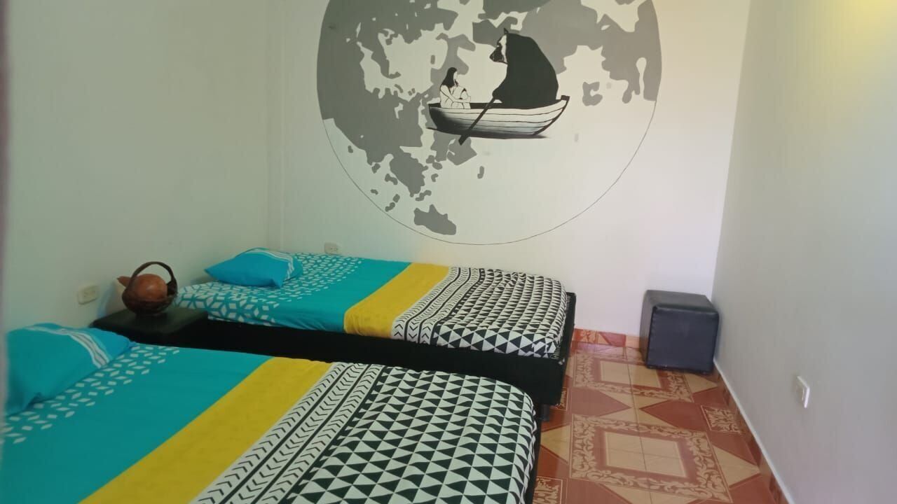 A room with two beds, a globe mural, a suitcase, and a kettle.
