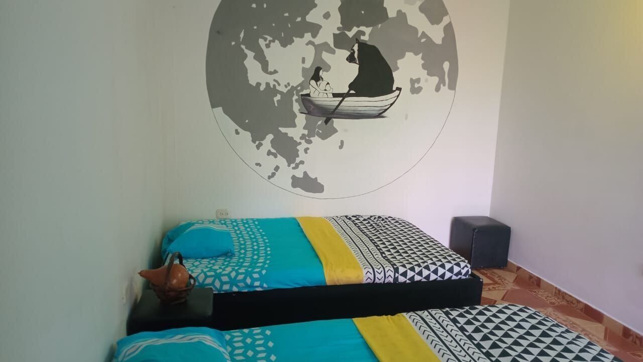 Una habitación con dos camas, un mural en la pared de un barco y una colcha estampada.