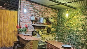 Een landelijke keuken met een bakstenen muur, hangende pannen en een houten aanrecht.