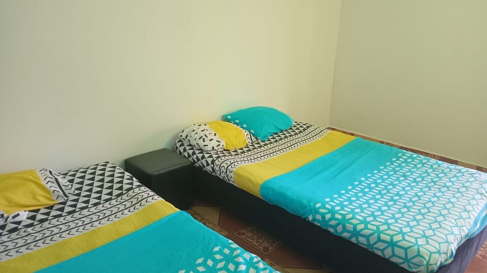 A small, single-bed room with a patterned bedspread and pillows.