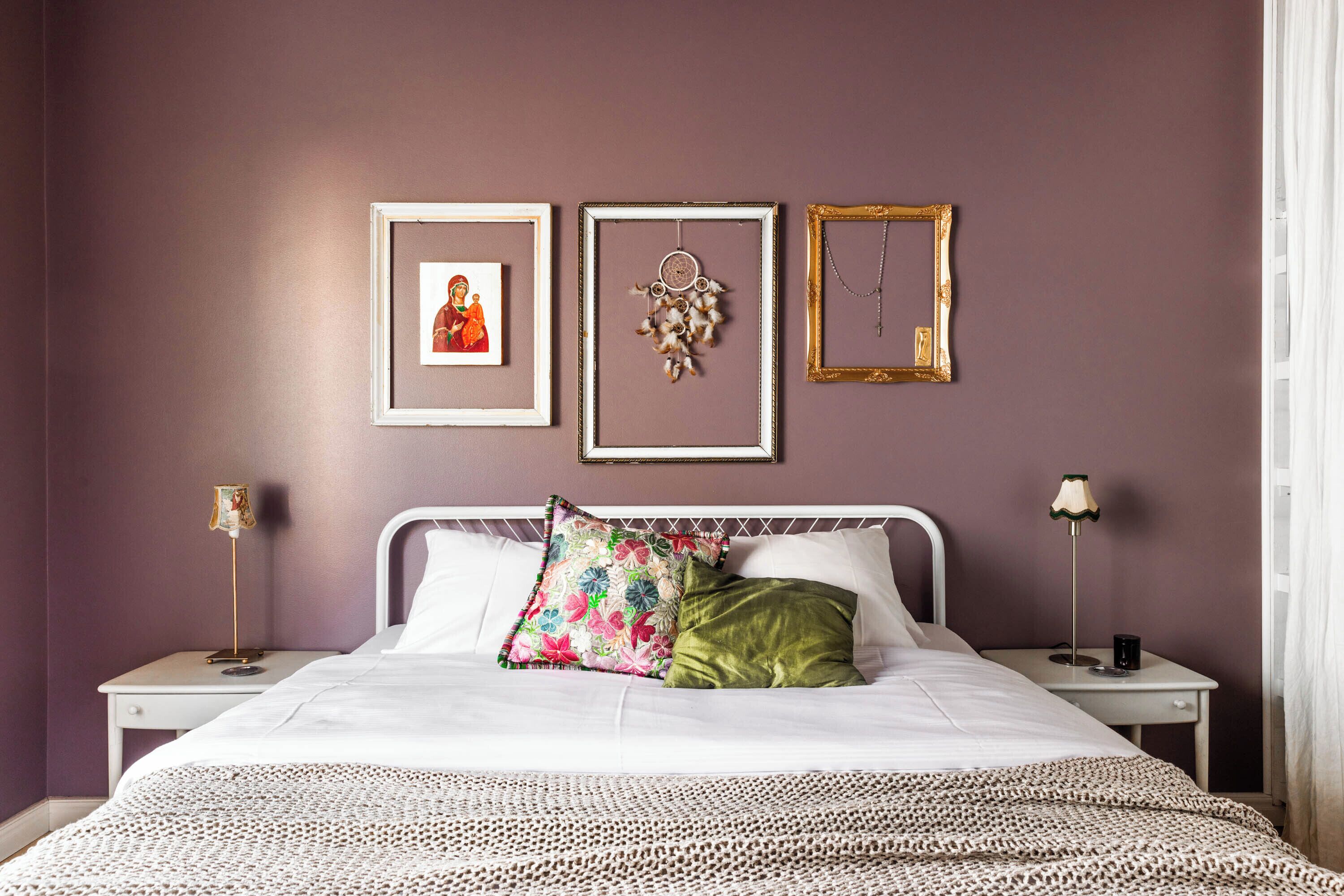 A bedroom with a bed, two bedside tables, and three framed pictures on the wall.