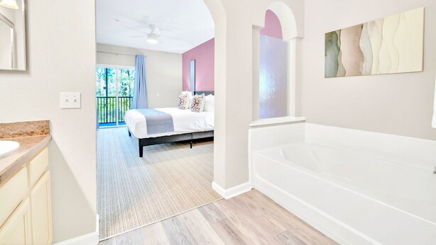 A modern bathroom with a large bathtub, a separate shower area, and a vanity with a sink. - Upstay Pet-friendly Condo with Pool near Disney (Winter Garden)
