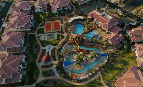 An aerial view of a resort with multiple swimming pools, a water slide, and a tennis court. - Arcadia 69 | PRIVATE Pool + Hot Tub + Sports Court (Santa Clara)