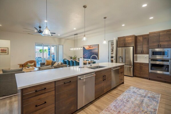 A modern kitchen with a large island, stainless steel appliances, and wooden cabinetry. - 2 Private Pools, Hot Tubs, Sport Courts, Fire Pits! (Santa Clara)