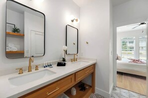 Un baño moderno con dos lavamanos, un espejo grande y un mueble de tocador de madera.