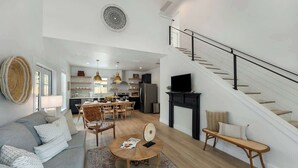 Amplia sala de estar con sofá, mesa de centro y una escalera que conduce a un nivel superior.