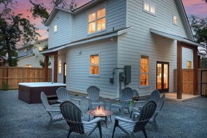 A two-story house with a patio area featuring outdoor seating and a fire pit.
