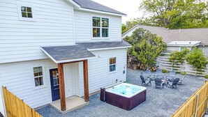 Una casa de dos pisos con un patio cubierto que incluye un jacuzzi y asientos al aire libre.