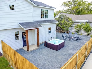 Une maison à deux étages dotée d’un patio couvert comprenant un jacuzzi et un espace salon extérieur.