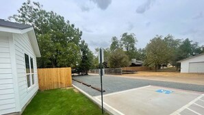 Un espace de stationnement comprenant une place réservée aux personnes handicapées, une clôture en bois et un bâtiment dont le revêtement extérieur est blanc.