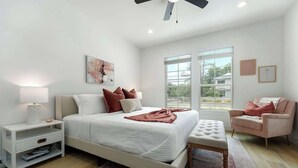 Un dormitorio con cama, mesita de noche, silla y ventana con vistas.