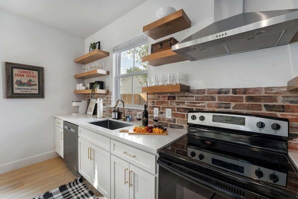 A modern kitchen with white cabinetry, a brick backsplash, and stainless steel appliances.