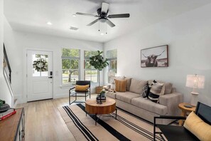 Ein modernes Wohnzimmer mit Sofa, Couchtisch und Deckenventilator.