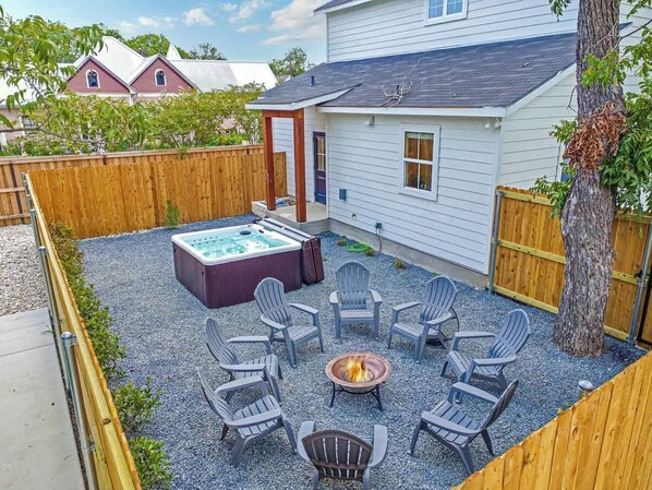 Un jardin avec un jacuzzi, un foyer extérieur et un espace salon extérieur.