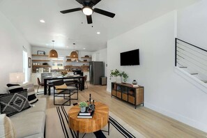Un salon moderne comprenant un coin repas, une cuisine et un escalier.