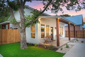 Une maison avec un patio couvert, une clôture en bois et un arbre dans la cour.