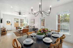 A spacious dining area with a dark wooden table set for a meal, surrounded by wooden chairs. - The Malbec: 3 Blocks to Main St w/Hot-Tub+Firepit! (Fredericksburg)