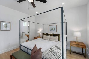A four-poster bed with a canopy, bedside tables with lamps, a bench, and framed artwork on the walls. - The Malbec: 3 Blocks to Main St w/Hot-Tub+Firepit! (Fredericksburg)