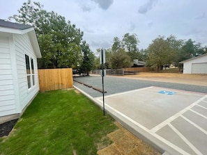 A parking area with a handicap parking space, a wooden fence, and a building with white siding.