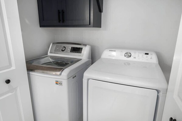 A laundry room with two washing machines and a cabinet above them.