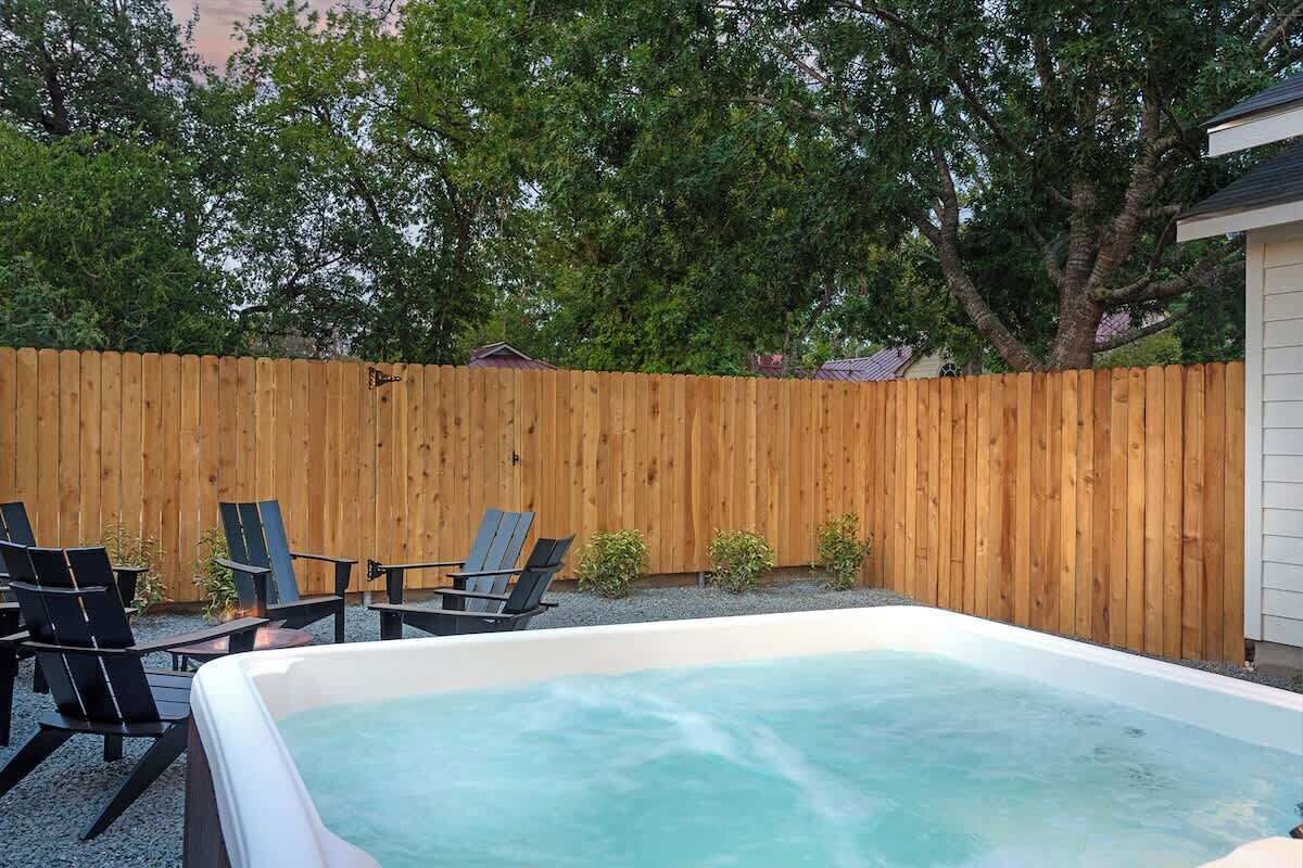 Ein Whirlpool mit Holzzaun und Gartenmöbeln im Garten.