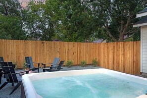 Un jacuzzi con valla de madera y sillas en un patio trasero.