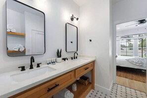 Ein modernes Badezimmer mit einem weißen Waschbecken, zwei Spiegeln und einer Holzausstattung.